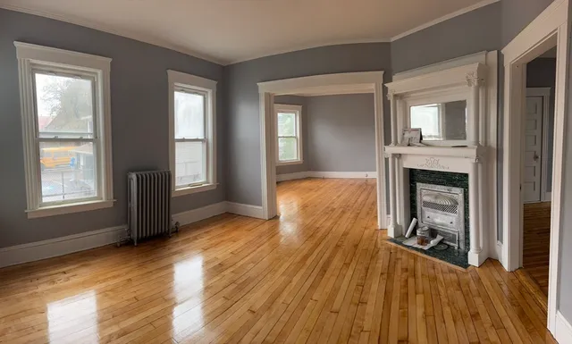 wooden floor fireplace and windows in an empty room