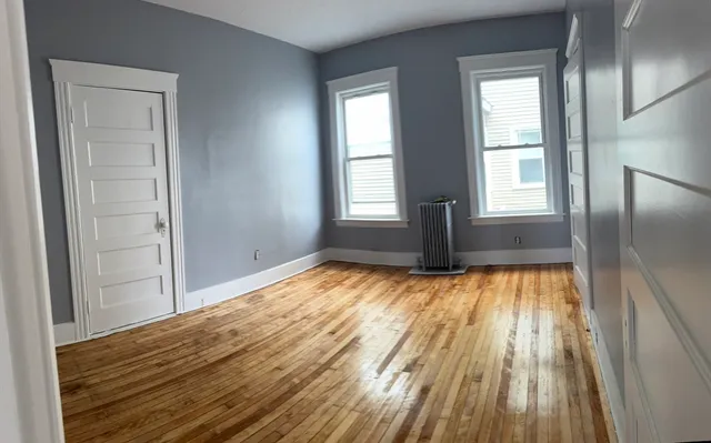 a view of empty room with wooden floor and fan