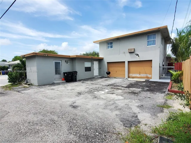 a view of a house with backyard and bushes