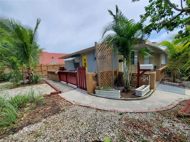 a palm tree sitting in front of a house with a yard