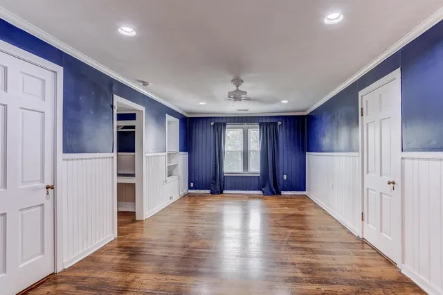 an empty room with wooden floor and windows