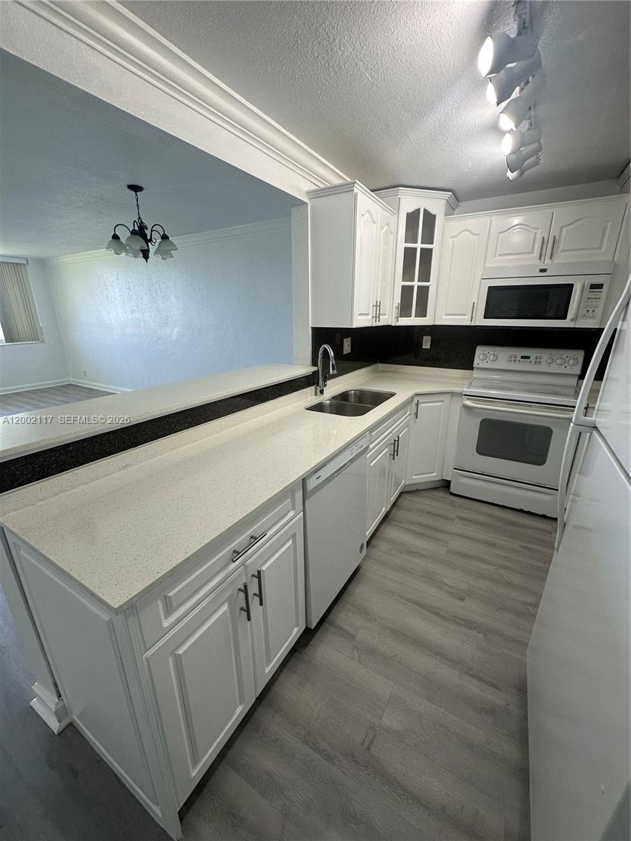 a kitchen with granite countertop white cabinets and white appliances