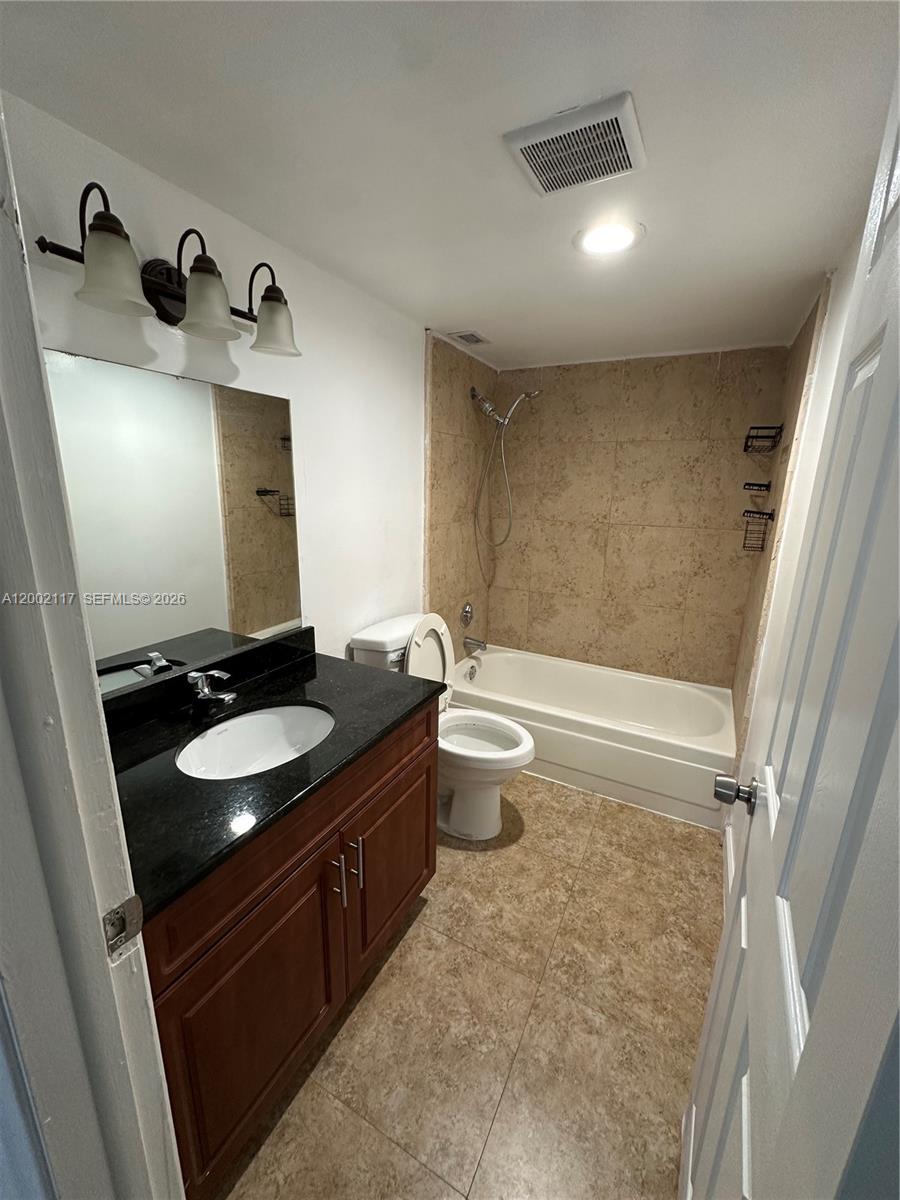 9001 Southwest 77th Avenue, Unit C702 Miami, FL 33156 - Photo 11 of 11 a bathroom with a granite countertop sink toilet and mirror