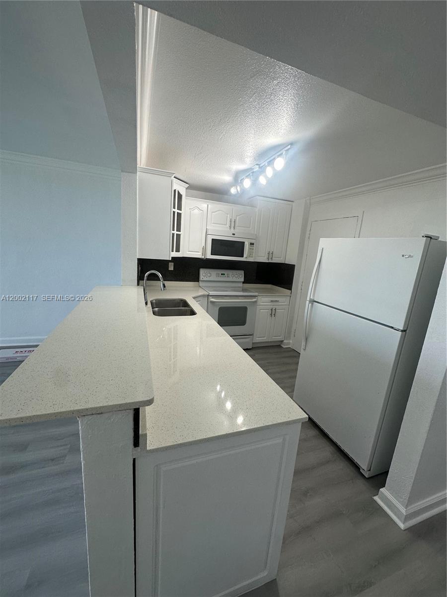 9001 Southwest 77th Avenue, Unit C702 Miami, FL 33156 - Photo 2 of 11 a kitchen with a sink a refrigerator and a stove