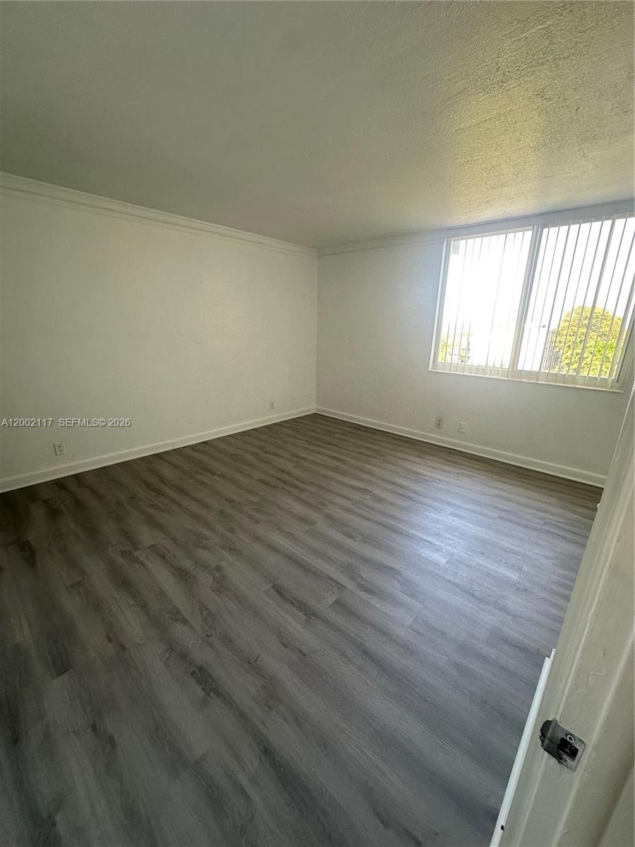 9001 Southwest 77th Avenue, Unit C702 Miami, FL 33156 - Photo 7 of 11 an empty room with wooden floor and windows