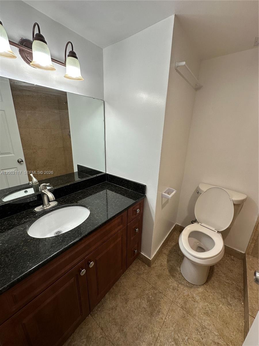 9001 Southwest 77th Avenue, Unit C702 Miami, FL 33156 - Photo 8 of 11 a bathroom with a granite countertop toilet sink and mirror