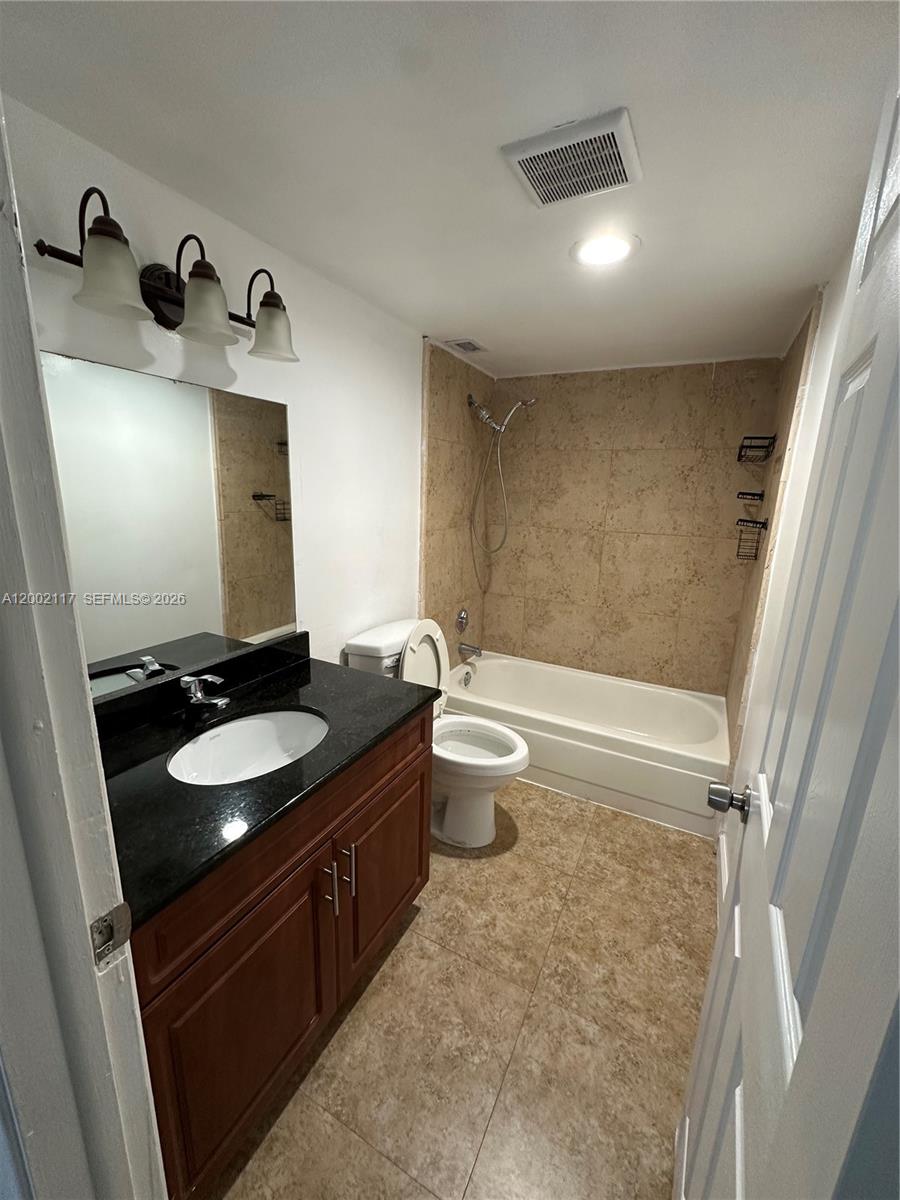 9001 Southwest 77th Avenue, Unit C702 Miami, FL 33156 - Photo 10 of 11 a bathroom with a granite countertop sink toilet and mirror