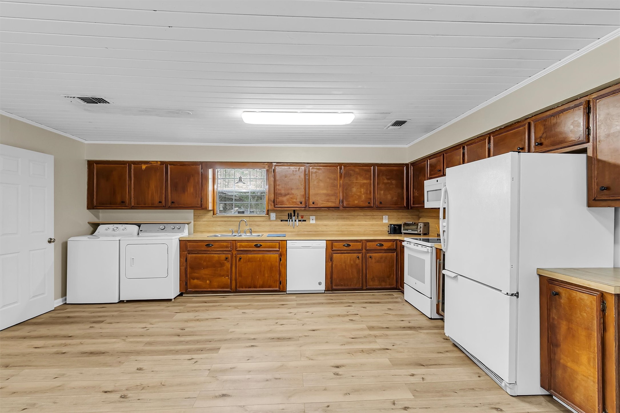 95 Main Street Huntsville, TX 77340 - Photo 29 of 30 a kitchen with a refrigerator a stove top oven a sink and dishwasher with wooden floor