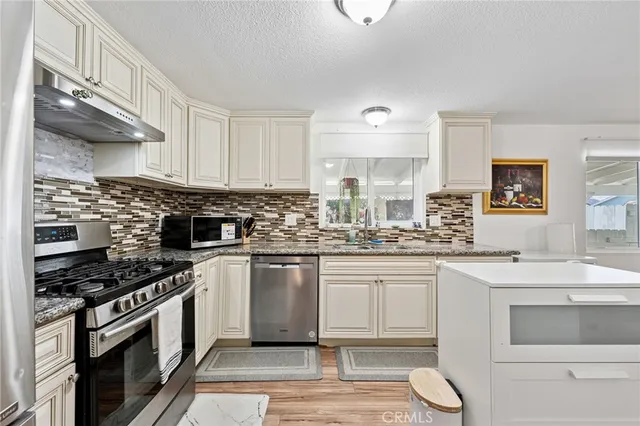 a kitchen with stainless steel appliances granite countertop a stove a sink and a microwave