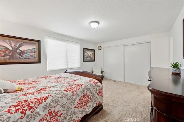a bedroom with a bed and a lamp on dresser