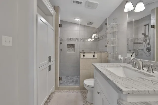 a bathroom with a granite countertop sink a toilet and shower