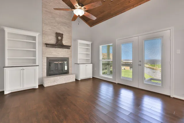 an empty room with wooden floor fireplace and windows
