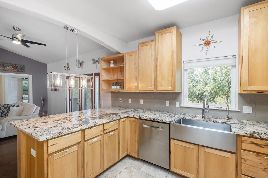 13326 Trautwein Road Austin, TX 78737 - Photo 7 of 38 Kitchen featuring stainless steel dishwasher, vaulted ceiling, decorative backsplash, a sink, and a ceiling fan
