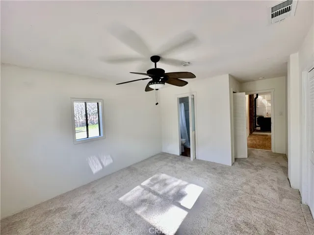 an empty room with windows and ceiling fan