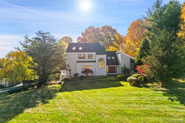 a front view of a house with a yard and a large tree