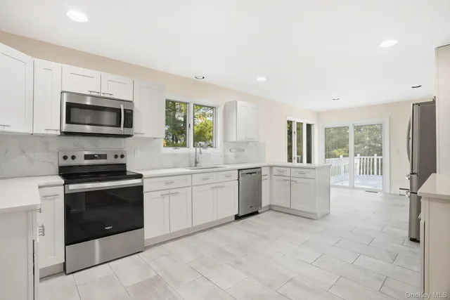 a kitchen with stainless steel appliances granite countertop a stove a sink and a microwave