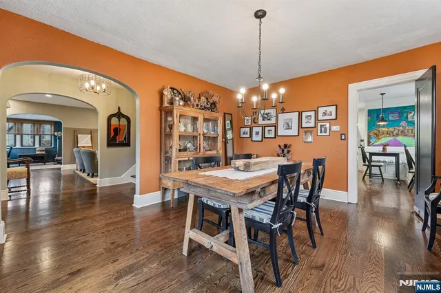 a dining room with furniture wooden floor a chandelier and a painting