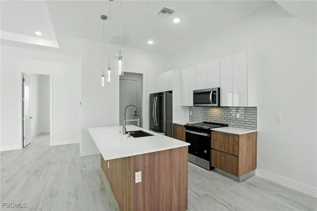 a kitchen with stainless steel appliances a stove top oven a sink dishwasher a refrigerator and a oven with wooden floor