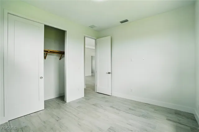 an empty room with wooden floor and a bathroom