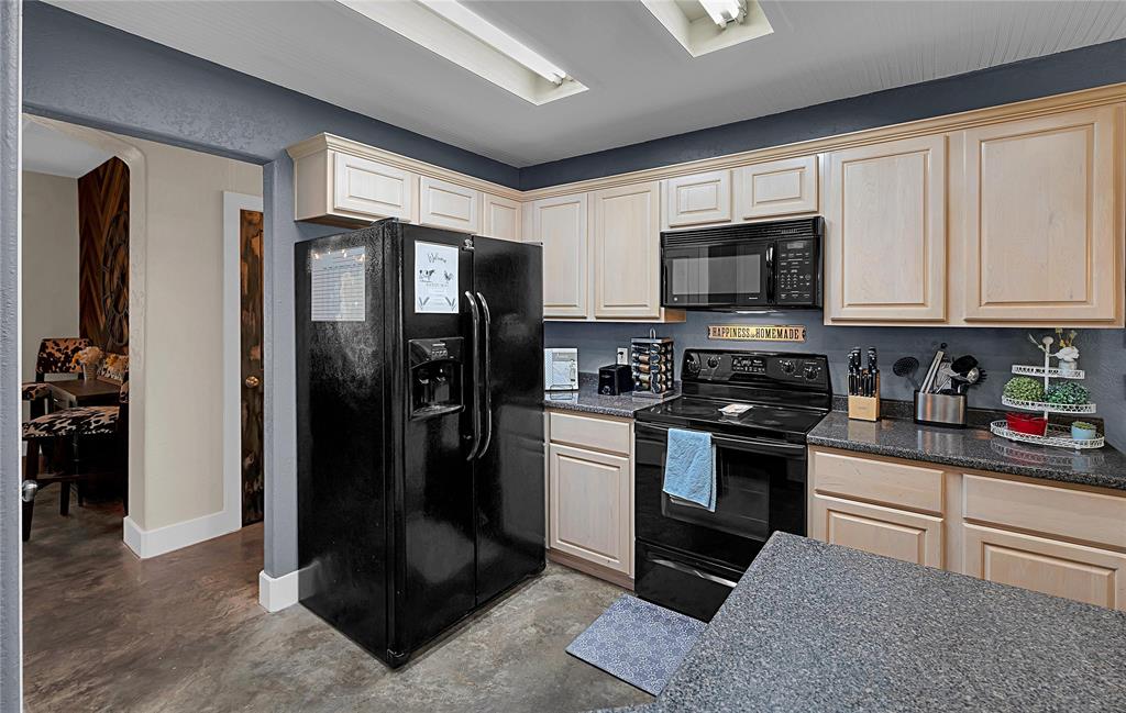 37 Bluebonnet Loop Morgan's Point Resort, TX 76513 - Photo 10 of 38 Kitchen featuring light wood-finish cabinetry, dark countertops, and a full suite of black appliances, including a microwave, range, and side-by-side refrigerator