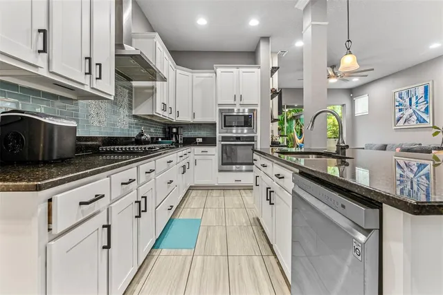 a kitchen with stainless steel appliances a sink a stove top oven a kitchen island and cabinets
