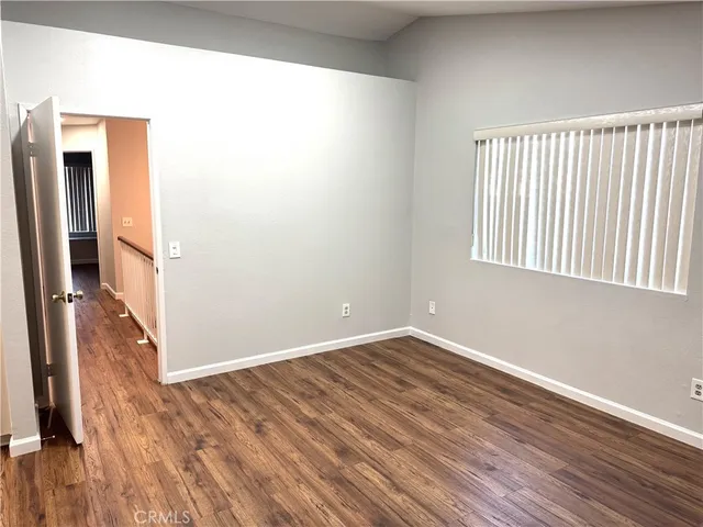 a view of a hallway with wooden floor and a bathroom