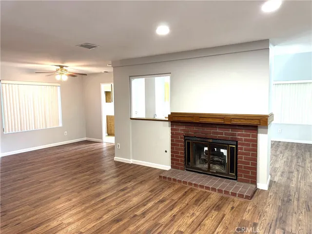 an empty room with wooden floor fireplace and windows
