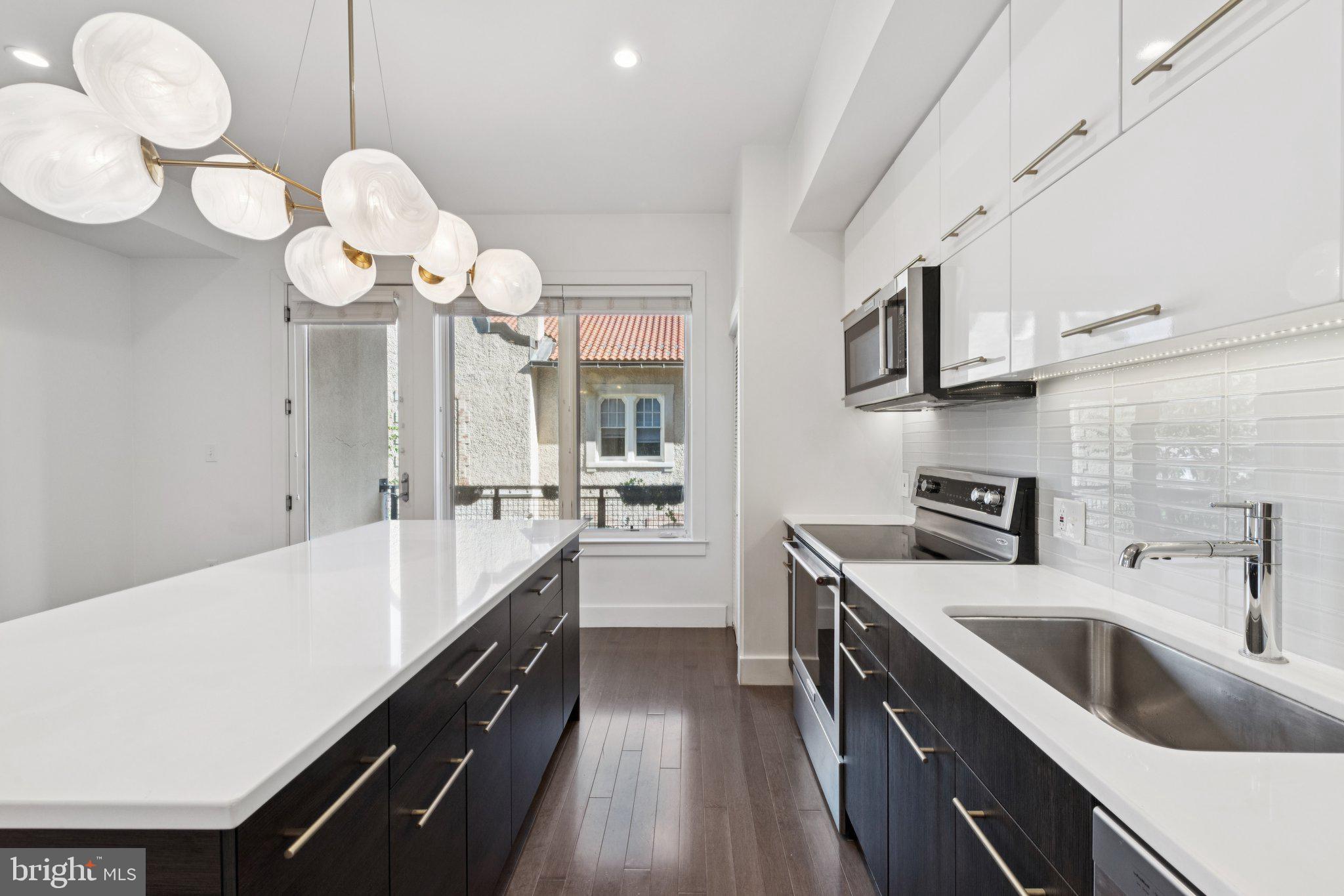 1767 Lanier Place Northwest, Unit 6 Washington, DC 20009 - Photo 29 of 49 a large kitchen with a large island in the center a sink stainless steel appliances and cabinets