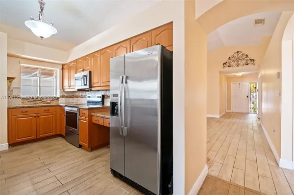 a kitchen with granite countertop a refrigerator and a stove top oven