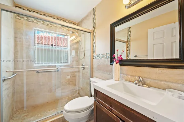 a bathroom with a granite countertop sink a toilet and shower