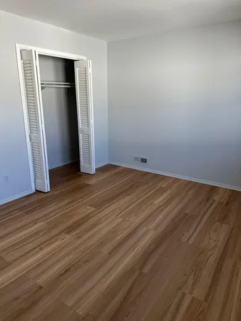 a view of an empty room with wooden floor and a bathroom