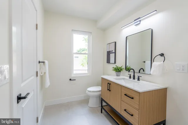 a bathroom with a double vanity sink toilet mirror and window