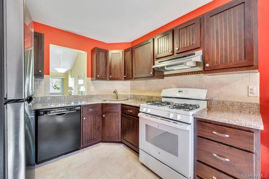 13 Mallard Path Coram, NY 11727 - Photo 8 of 39 a kitchen with stainless steel appliances granite countertop a stove top oven a sink and dishwasher a refrigerator with wooden cabinets