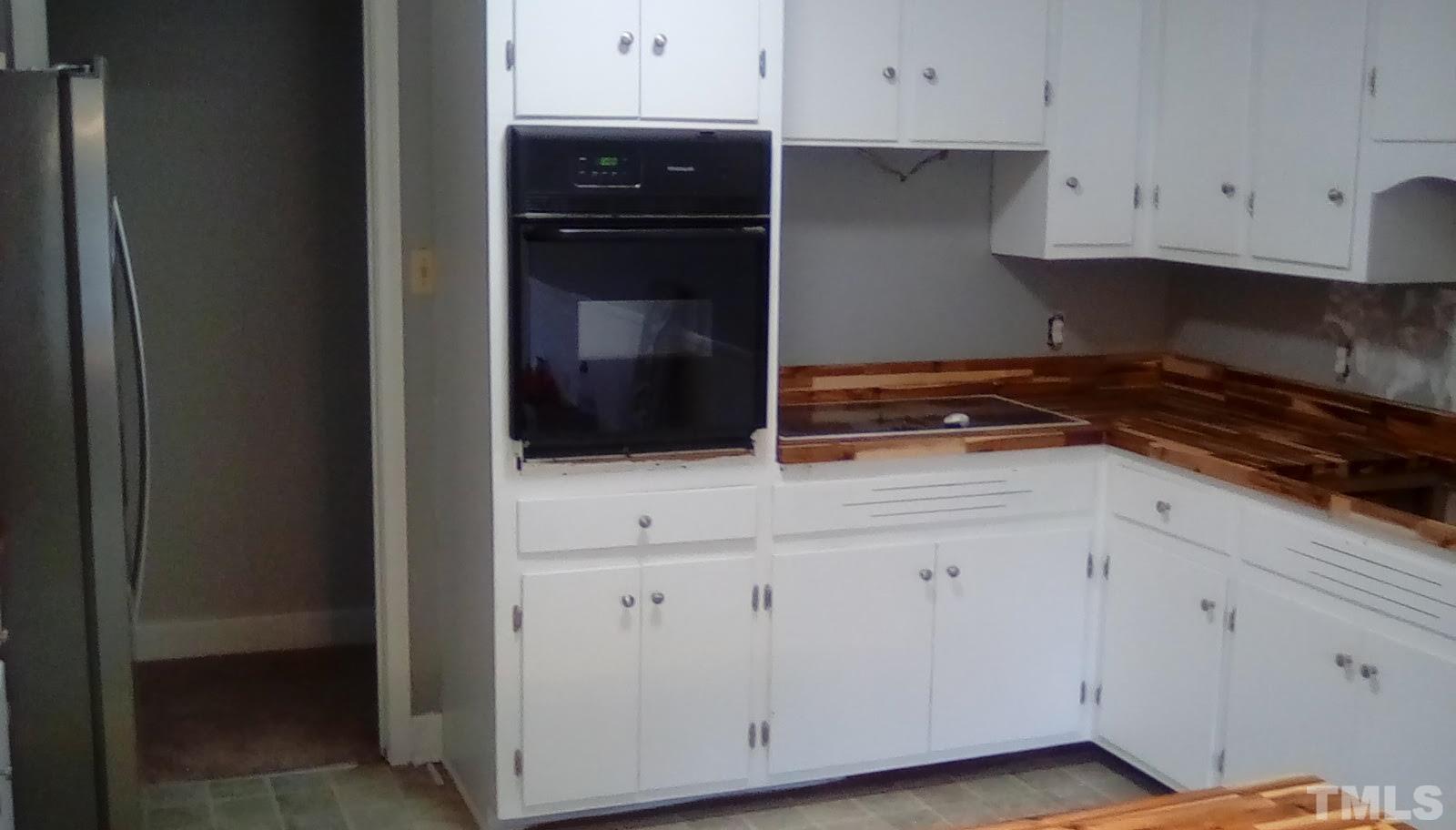 115 Kerr Lake Club Road Henderson, NC 27537 - Photo 8 of 20 a kitchen with white cabinets and black appliances