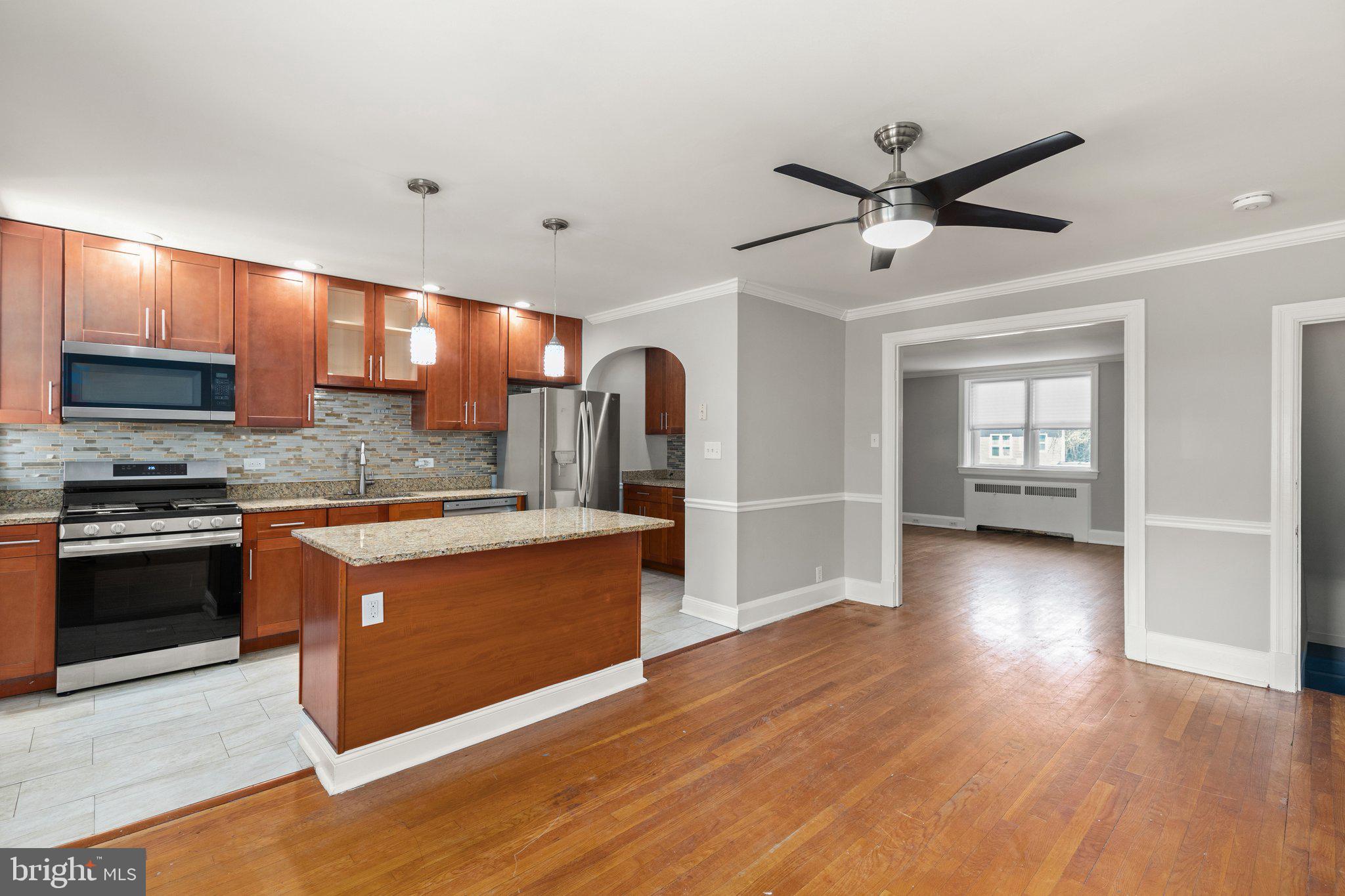 a large kitchen with stainless steel appliances granite countertop a stove and a wooden floors