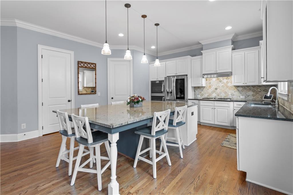 1625 Hamiota Ridge Alpharetta, GA 30004 - Photo 19 of 86 a kitchen with stainless steel appliances kitchen island granite countertop a wooden floor and white cabinets
