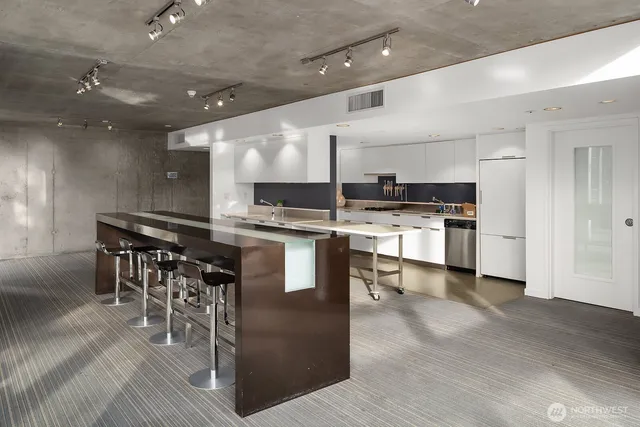 a kitchen with stainless steel appliances kitchen island granite countertop a table chairs sink and white cabinets