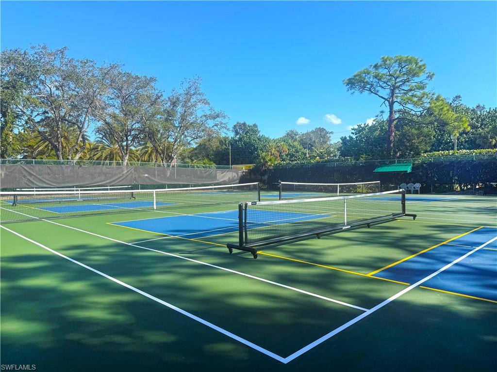 370 Emerald Bay Circle, Unit N8 Naples, FL 34110 - Photo 21 of 24 a tennis court with trees in the background