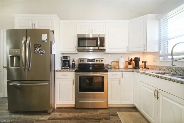 a kitchen with stainless steel appliances granite countertop a refrigerator stove a sink and a microwave