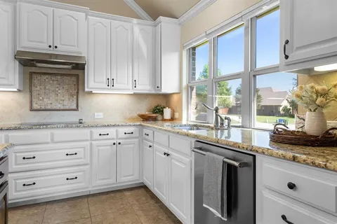 a kitchen with granite countertop white cabinets and white appliances