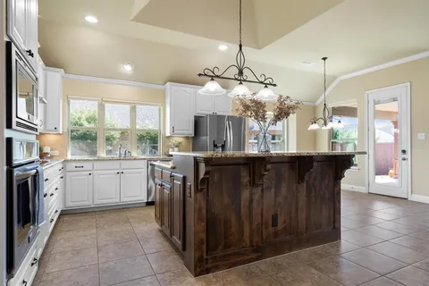 a kitchen with a refrigerator a sink dishwasher with a dining table and chairs