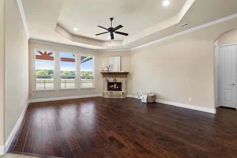 a view of an empty room with wooden floor fireplace and a window