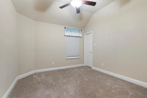 an empty room with a chandelier fan and windows