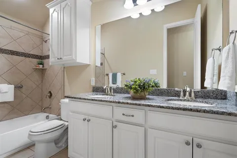 a bathroom with a granite countertop toilet sink and mirror
