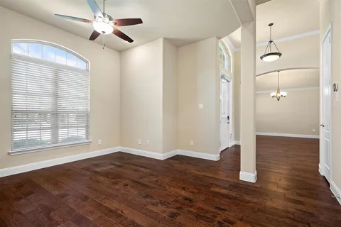 a view of empty room with wooden floor and fan