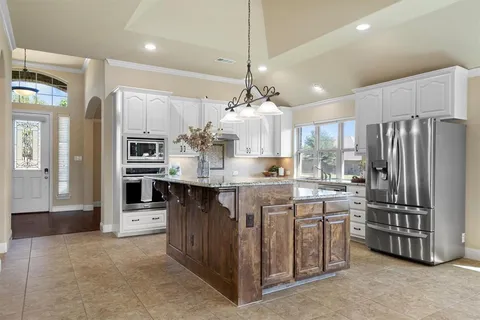 a kitchen with stainless steel appliances kitchen island granite countertop a refrigerator and a stove top oven