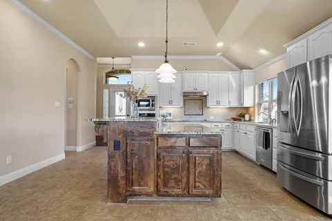 a kitchen with kitchen island granite countertop a sink a counter top space stainless steel appliances and cabinets
