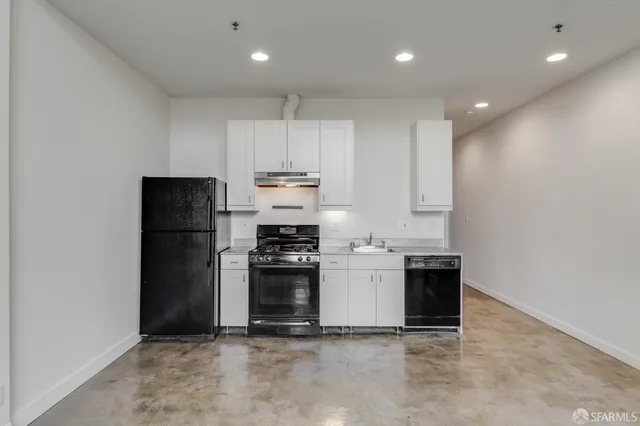 a kitchen with stainless steel appliances granite countertop white cabinets and a stove top oven