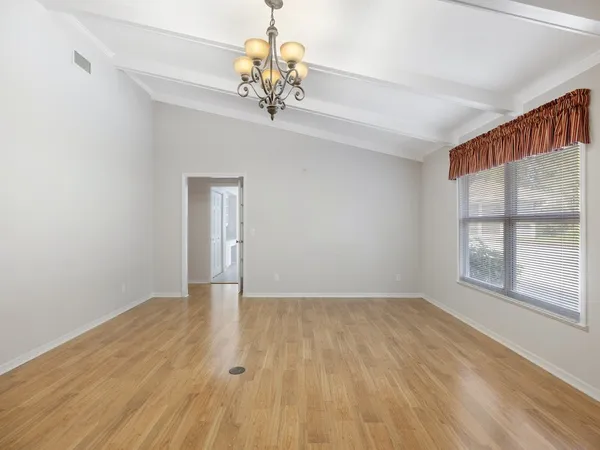 a view of an empty room with a window and wooden floor