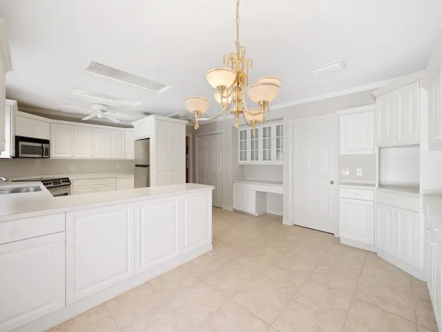 a large white kitchen with a lot of cabinets and stainless steel appliances